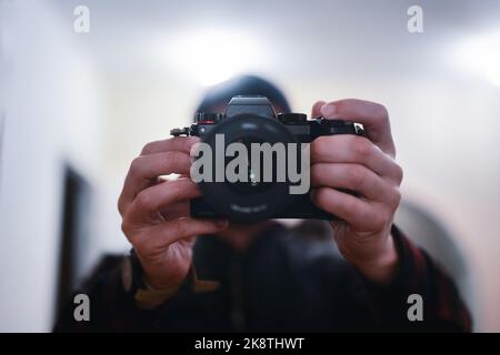 Mann mit moderner spiegelloser Vollformatkamera mit Fokus auf Auslöser Stockfoto