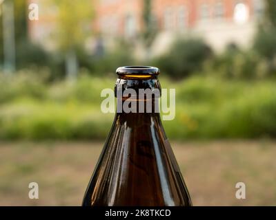 Nahaufnahme einer deutschen Bierflasche am Flaschenhals. Die konische Form aus braunem Glasmaterial ist üblich. Der Kronenkorken wurde vom Getränk entfernt. Stockfoto