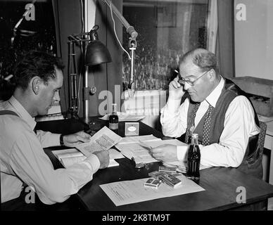 Oslo 19531012 die Parlamentswahlen 1953 waren die ersten Wahlen, nachdem die sogenannte Bauernabteilung aufgehoben wurde. Die Labour Party bekommt eine Mehrheit. Hier aus der Wahlnacht in der Nachrichtenagentur Norsk Telegrambyrå NTB, wo ​​Thorstein Diesen (Th) und Jan Frydenlund von der NRK während der Wahlnacht mit Ergebnissen und Trends Schritt halten. Kleine Coca Cola Flasche auf dem Tisch im Vordergrund. Foto: NTB / NTB Stockfoto
