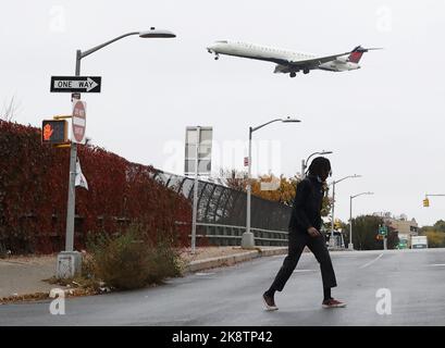 Queens, Usa. 24. Oktober 2022. Ein Fußgänger überquert die Ditmars Street, als ein Flugzeug am Montag, dem 24. Oktober 2022, im Stadtteil Queens in New York City den Flughafen LaGuardia anfliegt. Foto von John Angelillo/UPI Credit: UPI/Alamy Live News Stockfoto