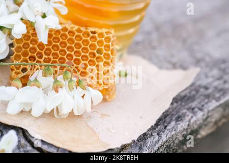 Scheibe von frischem Honig saß und Schüssel mit gelben Wabe Mit Akazienblüten Stockfoto