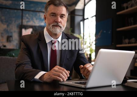 Reife Geschäftsmann arbeiten auf Laptop. Schöner reifer Geschäftsleiter sitzt in einem modernen Büro Stockfoto