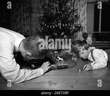 Oslo 195712. Heiligabend in der Familie Rørslett. Die Jungs spielen mit den Weihnachtsgeschenken, einem Zug und machen eine Zugstrecke auf dem Boden vor dem Weihnachtsbaum. Foto Sverre A. Børretzen / Aktuell / NTB Stockfoto