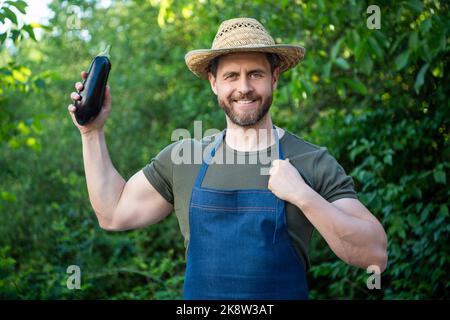 Mann Gemüsehändler in Strohhut mit reifen Auberginen Gemüse Stockfoto