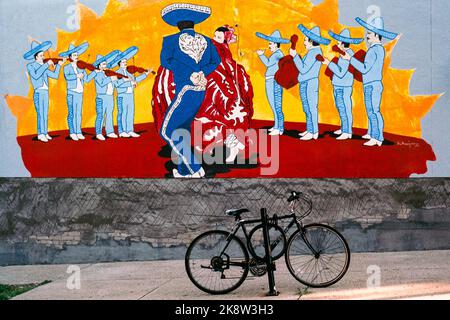 Ein farbenfroher Wandgemälde, auf dem mexikanische Tänzer abgebildet sind, sieht man vor einem schwarzen Fahrrad, das an einen Posten außerhalb eines mexikanischen Restaurants in Melrose, Massa, angekettet ist Stockfoto
