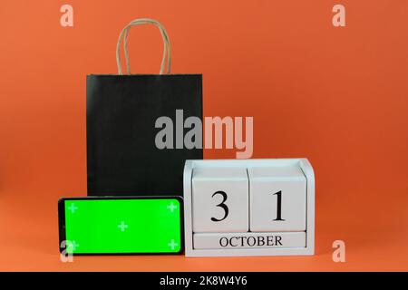 Oktober 31 auf Holzkalender, grünes Bildschirmtelefon und Papier schwarze Tasche Stockfoto