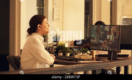 Büroangestellte, die Videocall-Meetings am Computer nutzen, um mit Menschen über die Webcam zu sprechen, um Ferngespräche über Internet-Telefonkonferenzen zu führen. Teilnahme an einer Online-Videokonferenz bei Sonnenuntergang. Stockfoto