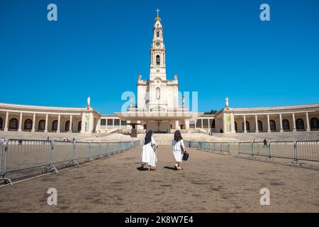 Das Heiligtum von Fatima, Portugal. Zwei Nonnen, die im Hintergrund vor der Basilika unserer Lieben Frau vom Rosenkranz vorbeigingen. Stockfoto