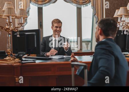 Ein männlicher Geschäftsmann checkt im Luxushotel ein und erhält die Schlüsselkarte von der Rezeption Stockfoto