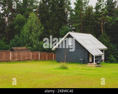 Malerische nordische Landschaft mit einem Holzhaus im skandinavischen Stil und einem vorderen Grasgrundstück. Konzept von Einfachheit, Ruhe, Harmonie Stockfoto