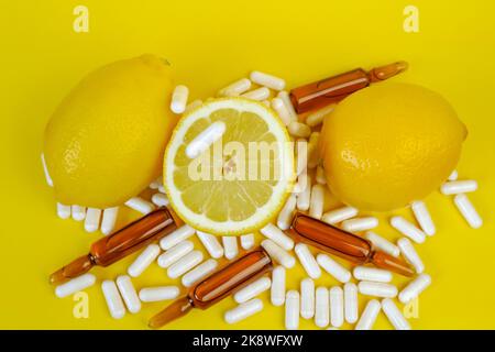 Vitamin C Tabletten auf hellgelbem Hintergrund.viele Pillen und Zitrusfrüchte. Fliegende Vitamin C weiße Pillen und gelbe Zitronen geschnitten Set .natürliche Frucht Stockfoto