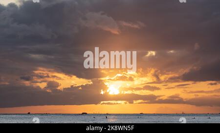 Atemberaubender Sonnenuntergang von Oahu in Hawaii mit Silhouetten von Surfern und Schwimmern. Stockfoto