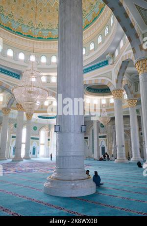 Das Innere der reich ausgestatteten Moschee mit blaugrünem Teppich, hohen Marmorsäulen und Gläubigen. Am riesigen, großen Wahrzeichen Hazret Sultan M Stockfoto