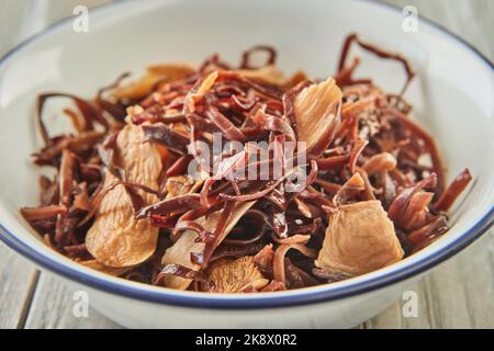 Getrocknete Schinaga-Pilze in Wasser in einer Schüssel auf Holzgrund eingeweicht Stockfoto