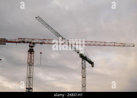 Danzig Polen Mai 2022 Silhouetten von Baukräne und unfertigen Wohngebäuden gegen den Sonnenaufgang über der Stadt. Wohnungsbau, Wohnblock Bau neuer Wohnhochhäuser. Vor dem Hintergrund des Sonnenuntergangs Himmel. Stockfoto