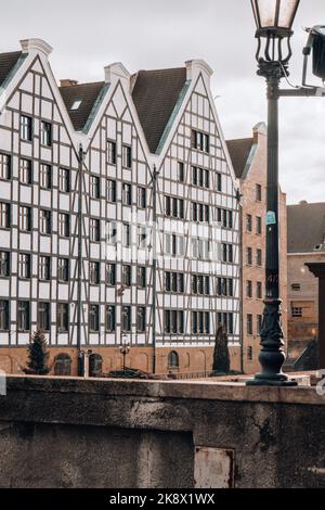 Danzig, Polen Mai 2022, moderne Gebäude über dem Motlawa-Fluss in der Altstadt. Tourismus auf dem Motlawa River. Neue Apartments-Architektur auf Granary Island Glasfenster mit Reflexionen. Touristisches Reiseziel Stockfoto