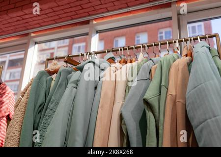 Bunte Damenkleider, Jacken, Hosen und andere Kleidung an Kleiderbügeln in einem Einzelhandelsgeschäft. Das Konzept von Mode und Shopping. Damenbekleidung im Kampf Stockfoto