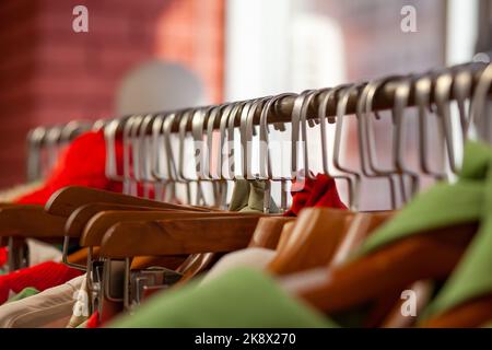 Bunte Damenkleider, Jacken, Hosen und andere Kleidung an Kleiderbügeln in einem Einzelhandelsgeschäft. Das Konzept von Mode und Shopping. Damenbekleidung im Kampf Stockfoto