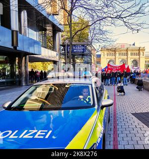 Hannover, 22. Oktober 2022: Junge, hübsche deutsche Polizistin fährt vor der kommunistischen Jugenddemonstrationsprozession Stockfoto