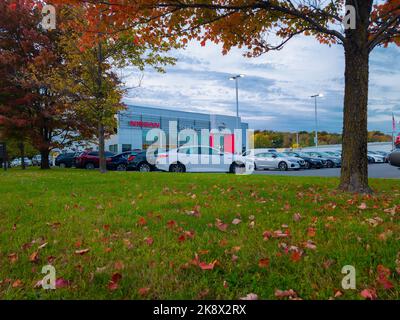 New Hartford, New York - 6. Okt 2022: Landschaft Herbstansicht des Außengebäudes des Autohauses Nissan Steet Ponte mit nagelneuen Autos, die vor dem Gebäude geparkt sind. Stockfoto