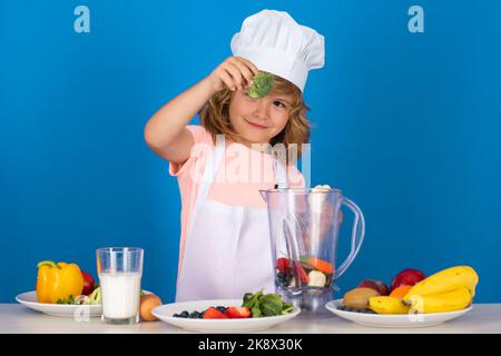 Kinderkoch halten Brokkoli isoliert auf blau. Lustige kleine Koch Koch Koch tragen einheitliche Kochmütze und Schürze gekocht Essen in der Küche. Stockfoto