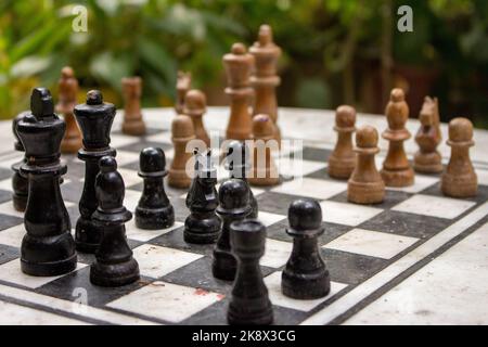 Outdoor-Schachbrett mit Figuren. Wettbewerbs- und Strategiekonzept. Intelligenter Sport. Konzept „Niederlage und Kampf“. Schach Holzstücke an Bord. Stockfoto