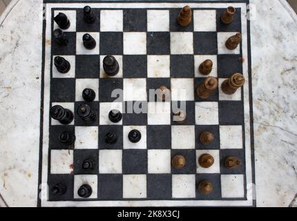 Steinschachbrett im Freien mit Figuren Draufsicht. Wettbewerbs- und Strategiekonzept. Konzept „Niederlage und Kampf“. Schach Holzstücke an Bord. Schachspiel. Stockfoto