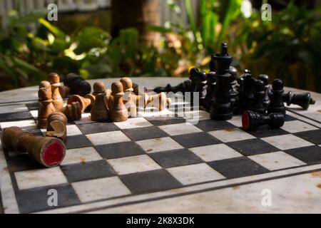 Outdoor-Schachbrett mit Figuren. Wettbewerbs- und Strategiekonzept. Intelligenter Sport. Konzept „Niederlage und Kampf“. Schach Holzstücke an Bord. Stockfoto