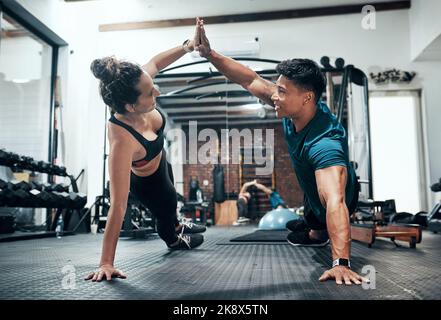 Wir erreichen mehr, wenn wir gemeinsam trainieren. Zwei sportliche junge Menschen trainieren gemeinsam im Fitnessstudio. Stockfoto
