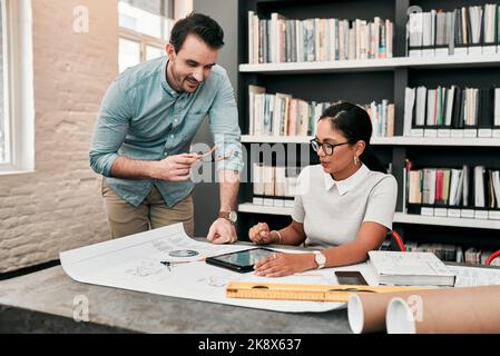 Genau das haben wir gesucht: Zwei aufstrebende junge Architekten, die ein digitales Tablet nutzen, während sie in einem modernen Büro zusammenarbeiten. Stockfoto