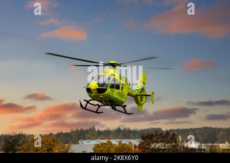 FinnHEMS, Finnish Helicopter Emergency Medical Services, medizinischer Hubschrauber hebt in der Stadt gegen den Sonnenuntergangshimmel ab. Stockfoto