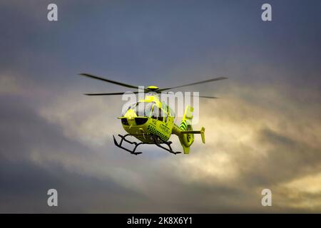 Medizinischer FinnHEMS-Hubschrauber im Flug gegen den dramatischen dunklen Himmel. FinnHEMS ist eine Abkürzung für Finnish Helicopter Emergency Medical Services. Stockfoto