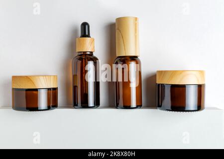 Set aus Flaschen ohne Marke und Gläsern aus dunklem Glas für Kosmetika. Auf weißem Hintergrund. Hautpflegekonzept. Modell Stockfoto