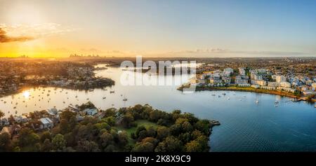 Farbenprächtiger Sonnenaufgang über der Skyline der Stadt Sydney vom Parramatta River aus - Panoramabild aus der Luft. Stockfoto