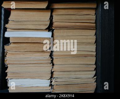 Kanten alter Bücher in zwei Stapeln in Bücherregal-Nische. Papier vergilbt von der Zeit. Stockfoto