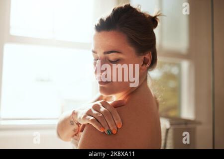 Was die Haut will, bekommt die Haut. Eine attraktive junge Frau, die während ihrer morgendlichen Schönheitsroutine Feuchtigkeitscreme aufbringt. Stockfoto
