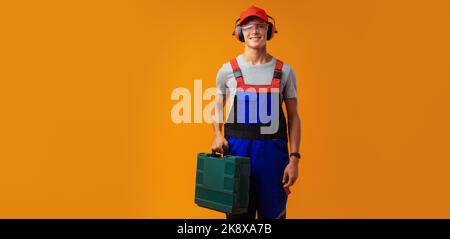 Porträt eines jungen Vorarbeiters mit Werkzeugkasten auf gelbem Hintergrund Stockfoto