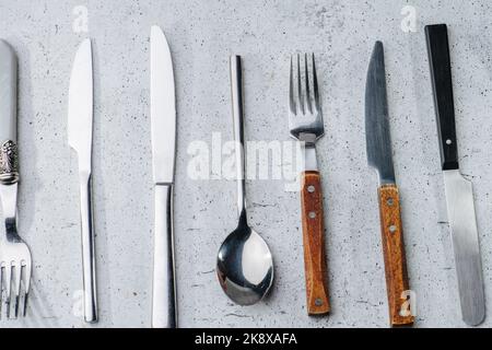 Besteck auf einer Tischoberfläche. Messer, Gabeln und Löffel aus Edelstahl Stockfoto