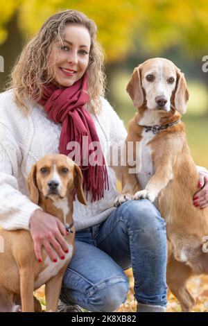 Porträt einer jungen Frau im Herbst-Outfit mit ihren beiden Haustieren. Stockfoto