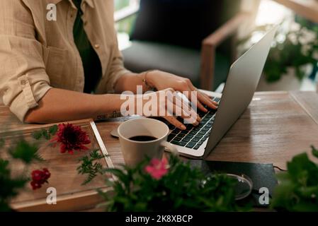 Die meisten meiner Kunden kaufen meine Werke online. Eine unkenntliche Floristin, die in ihrem Geschäft an einem Laptop arbeitet. Stockfoto