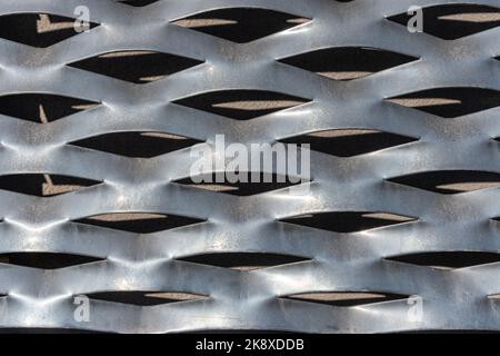 Struktur der perforierten Stanzplatte aus Metallblech - Vorderansicht. Lichtreflexion und Schatten. Stockfoto