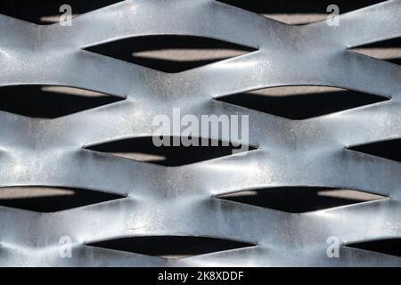 Struktur der perforierten Stanzplatte aus Metallblech - Vorderansicht. Lichtreflexion und Schatten. Stockfoto