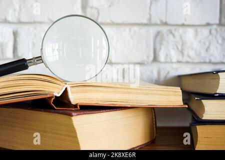 Lupe auf einem offenen Buch als Konzept von Wissen und Forschung. Stockfoto