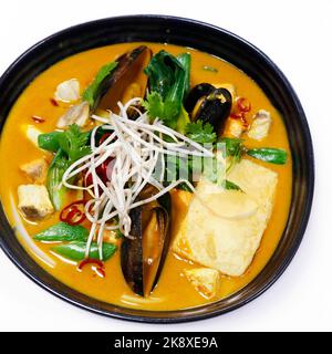 Laksa-Suppe, traditionelle asiatische Meeresfrüchte-Suppe mit Kokosnussgeschmack und Reisnudel in einer Schüssel mit weißem Hintergrund Stockfoto