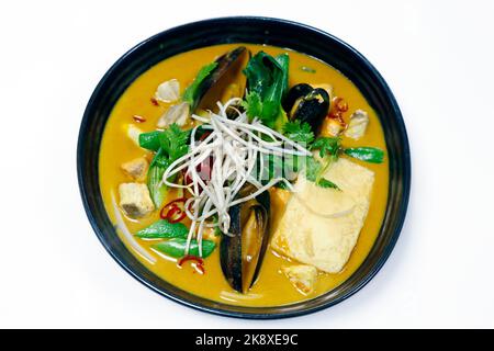 Laksa Nudelsuppe, traditionelle asiatische Meeresfrüchte Suppe mit Kokosnussgeschmack oder Brühe mit Reisnudel in einer Schüssel auf weißem Hintergrund Stockfoto