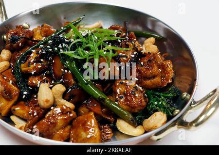 Gebratenes chinesisches Huhn mit Brokkoli, Bok Choy und Cashewnuss in Soja-Sesamauster-Sauce rühren Stockfoto