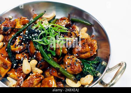 Wok gebratenes chinesisches Huhn mit Brokkoli, Bok Choy und Cashewnuss in Sojasame-Austernsauce und weißem Hintergrund Stockfoto