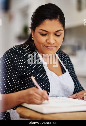Wer braucht nicht ein extra bisschen Einkommen. Ein Notizen machen, während eine Schürze tragen. Stockfoto