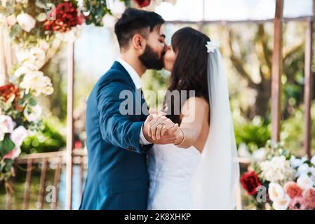 Sie entschieden sich, ihre Ewigkeit zusammen zu verbringen. Ein unkenntlich frisch verheiratetes Paar küsste sich, während es an ihrem Hochzeitstag die Hände hielt. Stockfoto