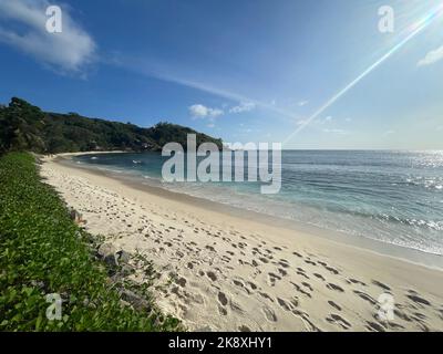 Der Strandsand auf den Seychellen ist von Fußabdrücken und flachen Wellen an der Küste bedeckt Stockfoto